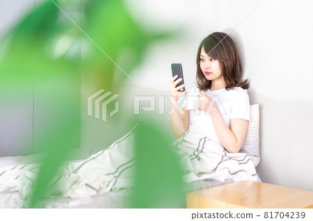 Young woman using a smartphone in bed Young woman using a smartphone in bed 81704239