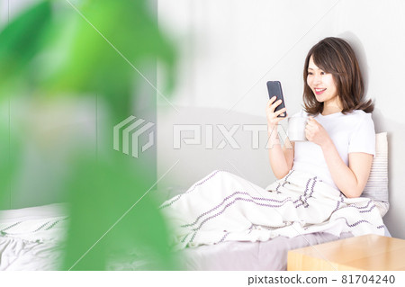 Young woman using a smartphone in bed Young woman using a smartphone in bed 81704240