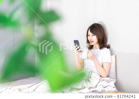 Young woman using a smartphone in bed Young woman using a smartphone in bed 81704241