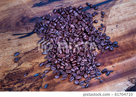 Macro photography top view of a heap fresh roasted coffee beans on a wooden background. High resolution detailed close up of brown roasted coffee beans on tropical wood table. Wallpaper image Macro photography top view of a heap fresh roasted coffee beans on a wooden background. High resolution detailed close up of brown roasted coffee beans on tropical wood table. Wallpaper image 81704710