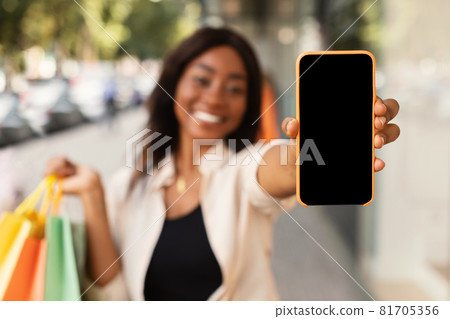 Black woman showing empty smartphone screen holding bags Black woman showing empty smartphone screen holding bags 81705356