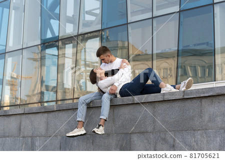 Smiling girl put her head on her boyfriend's lap. Guy looking on his girlfriend. Young couple in the city. Romantic date 81705621