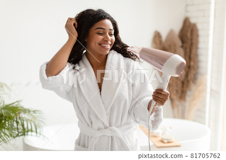 Joyful Black Female Using Hairdryer Drying Wet Hair In Bathroom Joyful Black Female Using Hairdryer Drying Wet Hair In Bathroom 81705762
