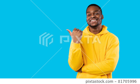 Smiling African Guy Pointing Thumb Finger Aside Over Blue Background Smiling African Guy Pointing Thumb Finger Aside Over Blue Background 81705996