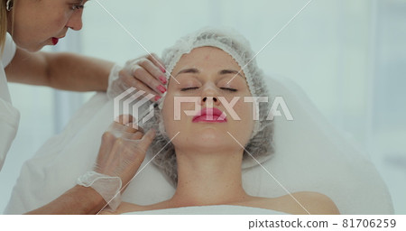 Beautician doctor makes injections into the skin of the face of a young beautiful woman. Top view close-up shot of platelet rich plasma face injections procedure. 81706259