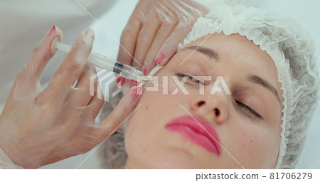 Close-up of beauty injection procedure in modern beauty clinic. injection with syringe into female cheek. Beautician performing mesotherapy and face lifting treatment in beauty salon. Close-up of beauty injection procedure in modern beauty clinic. injection with syringe into female cheek. Beautician performing mesotherapy and face lifting treatment in beauty salon. 81706279