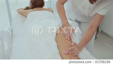 Woman hands doing professional massage to a woman on a massage table. Masseur doing massage on woman body in the spa salon. Beauty treatments. Woman hands doing professional massage to a woman on a massage table. Masseur doing massage on woman body in the spa salon. Beauty treatments. 81706296