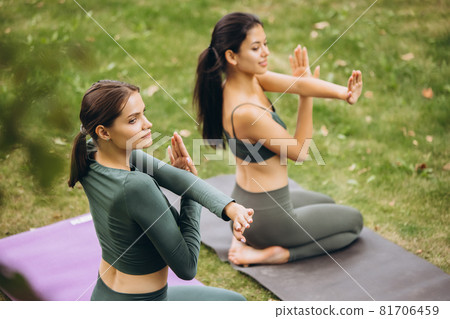Top back view of two fit girls practising yoga on open air on warm summer day Top back view of two fit girls practising yoga on open air on warm summer day 81706459
