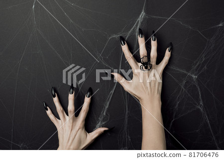 Hands with long black nails and spider ring on a black background with cobwebs. Happy Halloween holiday concept Hands with long black nails and spider ring on a black background with cobwebs. Happy Halloween holiday concept 81706476
