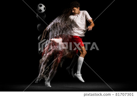 Young professional athlete playing football isolated on black background. Stroboscope effect 81707301