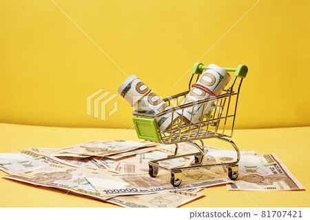 Buying us dollars in Uzbekistan. US dollars roll in shopping trolley and pile of Uzbek sums. Uzbek money and us dollar money exchange 81707421