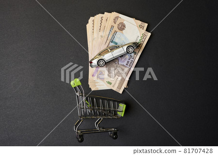 Buy auto insurance in Uzbekistan. Shopping cart, Uzbek sums and car toy. Concept of auto vehicle insuarance in Uzbekistan. Pile of 100000 sums and modern automobile toy 81707428