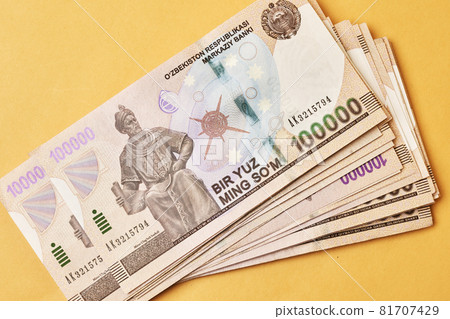 Pile of Uzbek sums on yellow. Uzbek currency money bill. A stack of one hundred thousand Uzbek sum. Uzbek money. 100000 sum 81707429