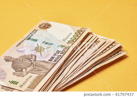 Pile of Uzbek sums on yellow. Uzbek currency money bill. A stack of one hundred thousand Uzbek sum. Uzbek money. 100000 sum 81707437