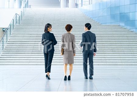 A business team of men and women in suits walking at the entrance of the office 81707958