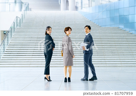 A business team of men and women in suits walking at the entrance of the office 81707959