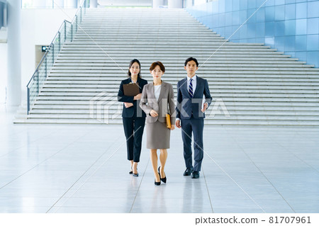 Male and female business team in suits walking in the office corridor 81707961