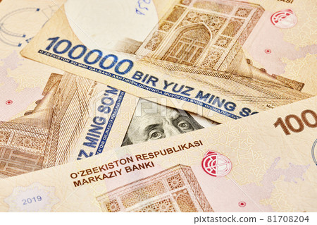 US dollar banknote and Uzbek sums. Concept of exchange rate, Uzbek sum to us dollar. Money exchange in Uzbekistan. Pile of Uzbek money sum and American dollar bill 81708204