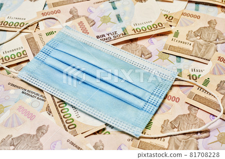 Uzbek currency sum weakening during Covid-19 pandemic. Pile of Uzbek sum currency money bill and medical face mask. A stack of one hundred thousand Uzbek sum and face mask. Value of Uzbek money Uzbek currency sum weakening during Covid-19 pandemic. Pile of Uzbek sum currency money bill and medical face mask. A stack of one hundred thousand Uzbek sum and face mask. Value of Uzbek money 81708228