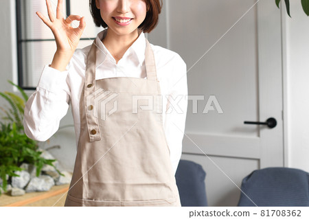 一個穿著微笑圍裙的年輕女子在室內 一個穿著微笑圍裙的年輕女子在室內 81708362
