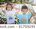 Two children relaxing in a sunny summer garden. A little girl and a little boy are playing in the park. 81709295