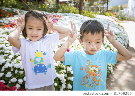 Two children relaxing in a sunny summer garden. A little girl and a little boy are playing in the park. Two children relaxing in a sunny summer garden. A little girl and a little boy are playing in the park. 81709295