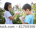 Two children relaxing in a sunny summer garden. A little girl and a little boy are playing in the park. 81709306