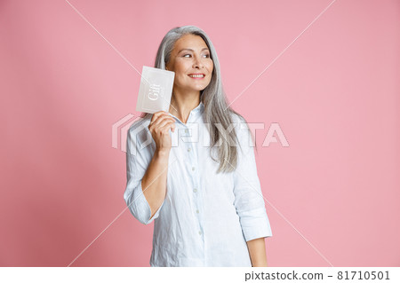 Pretty silver haired Asian woman holds gift card having ideas in studio 81710501