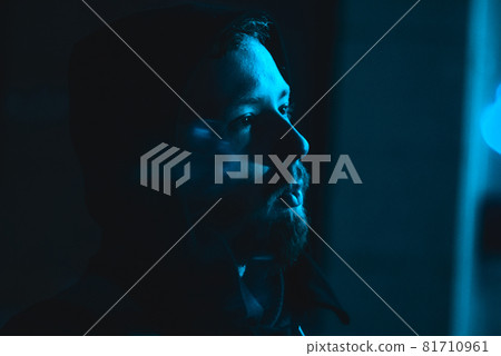 Portrait of smoking handsome man in a hood at the dark with cold blue light Portrait of smoking handsome man in a hood at the dark with cold blue light 81710961