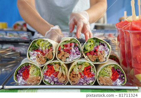 Selling meat and vegetable wraps and fruits at the Asian street festival 81711324