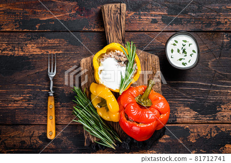 Roast bell pepper stuffed with beef meat, rice and vegetables on a wooden board. Dark wooden background. Top view 81712741