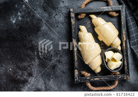 Raw fresh croissant in a wooden tray. Black background. Top view. Copy space Raw fresh croissant in a wooden tray. Black background. Top view. Copy space 81716422