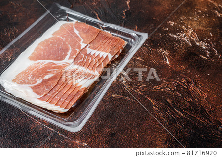 Italian prosciutto crudo or jamon in a vacuum package. Dark background. Top View. Copy space Italian prosciutto crudo or jamon in a vacuum package. Dark background. Top View. Copy space 81716920