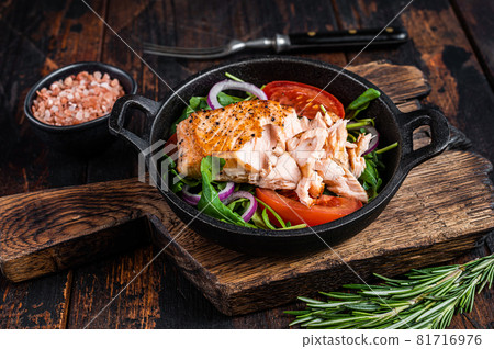 Grilled salmon fish fillet steak with fresh salad arugula, avocado and tomato in a pan. Dark wooden background. Top view 81716976