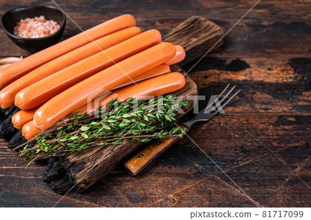 Frankfurter sausages on wooden cutting board. Dark Wooden background. Top view. Copy space 81717099