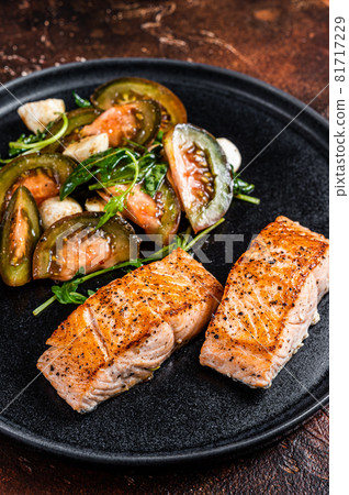 Grilled Salmon Fillet Steaks with arugula and tomato salad on a plate. Dark background. Top view 81717229