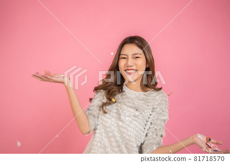 Portrait of a cheerful beautiful Asian womanl wearing dress standing standing under confetti rain and celebrating isolated over pink background Portrait of a cheerful beautiful Asian womanl wearing dress standing standing under confetti rain and celebrating isolated over pink background 81718570