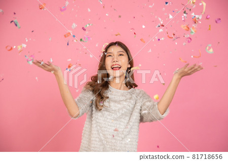 Portrait of a cheerful beautiful Asian womanl wearing dress standing standing under confetti rain and celebrating isolated over pink background Portrait of a cheerful beautiful Asian womanl wearing dress standing standing under confetti rain and celebrating isolated over pink background 81718656