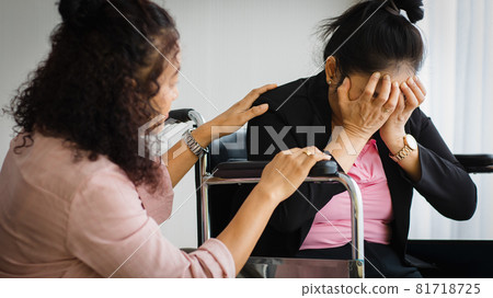 Middle age senior Asian woman take care and support female with headaches with stroke attacks on wheelchair. Concept of brain and head problem Middle age senior Asian woman take care and support female with headaches with stroke attacks on wheelchair. Concept of brain and head problem 81718725