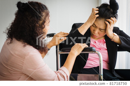 Middle age senior Asian woman take care and support female with headaches with stroke attacks on wheelchair. Concept of brain and head problem Middle age senior Asian woman take care and support female with headaches with stroke attacks on wheelchair. Concept of brain and head problem 81718730