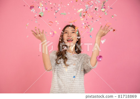 Portrait of a cheerful beautiful Asian womanl wearing dress standing standing under confetti rain and celebrating isolated over pink background Portrait of a cheerful beautiful Asian womanl wearing dress standing standing under confetti rain and celebrating isolated over pink background 81718869