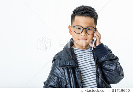Lovely cutout portrait of smart Asian boy wearing glasses, horizontal striped shirt, and black casual jacket contacting someone by using smartphone to call out and waiting for answering Lovely cutout portrait of smart Asian boy wearing glasses, horizontal striped shirt, and black casual jacket contacting someone by using smartphone to call out and waiting for answering 81719660