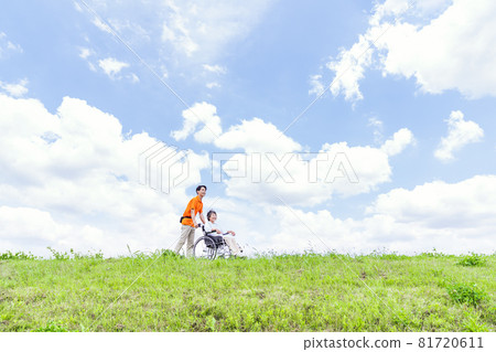 A caregiver pushing a wheelchair A caregiver pushing a wheelchair 81720611