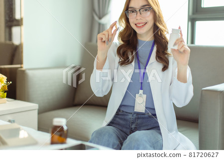 Young asian woman doctor looking at camera.Smiling female pharmacist holding a pill, health care and prevention concept, hand close up. Young asian woman doctor looking at camera.Smiling female pharmacist holding a pill, health care and prevention concept, hand close up. 81720627