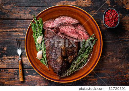Roasted hanger or Onglet sliced beef meat steak on a rustic plate with cleaver. Dark wooden background. Top View 81720891