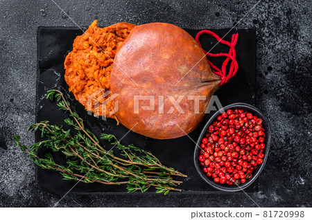 Balearic Sobrassada cured meat sausage from ground pork, paprika and spices. Black background. Top view 81720998