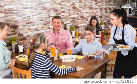 Girl is bringing salad and juice to young visitors Girl is bringing salad and juice to young visitors 81721035