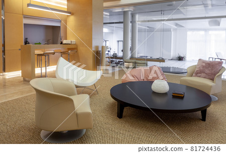 Coffee table and armchairs in living room on background of home gym with pool 81724436