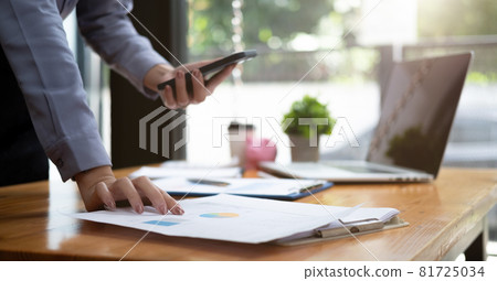 Business woman discussing on stockmarket charts in office, working on smart phone and laptop computer 81725034