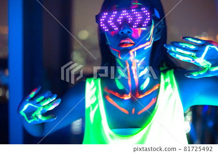 Neon asian woman dancing. Fashion model woman in neon light, portrait of beautiful model with fluorescent make-up, Art and future design of female disco dancer posing in UV, colorful make up. Neon asian woman dancing. Fashion model woman in neon light, portrait of beautiful model with fluorescent make-up, Art and future design of female disco dancer posing in UV, colorful make up. 81725492